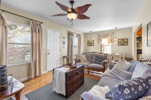 A cozy living room with a sofa, a wooden chest, and a ceiling fan.