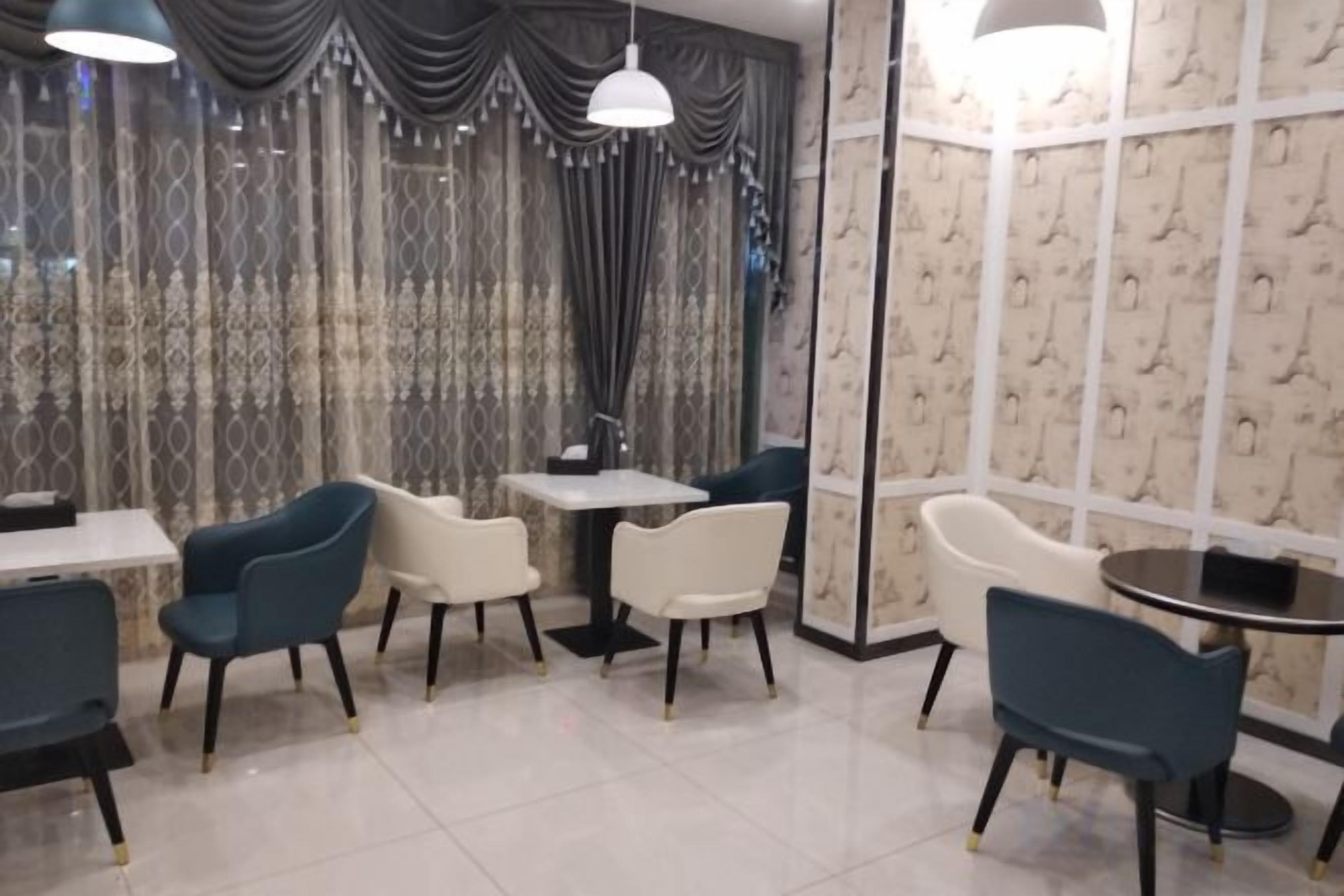 Interior de restaurante con mesas, sillas, un muro con diseño y una cortina.