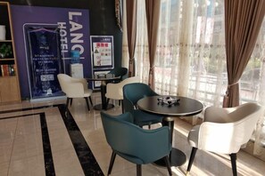 A hotel lobby with a reception desk, seating area with chairs, a small table, and a large window with curtains. - LanOuShangPin Hotel (Shan County Central Hospital Yinzuo) (Shan County)