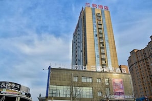 Un edificio de hotel alto con varios pisos y un letrero llamativo en la parte superior.