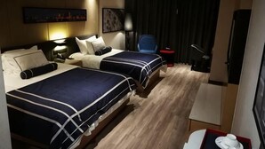 Une chambre d’hôtel avec deux lits, un bureau, une chaise, une télévision et une fenêtre avec des rideaux.