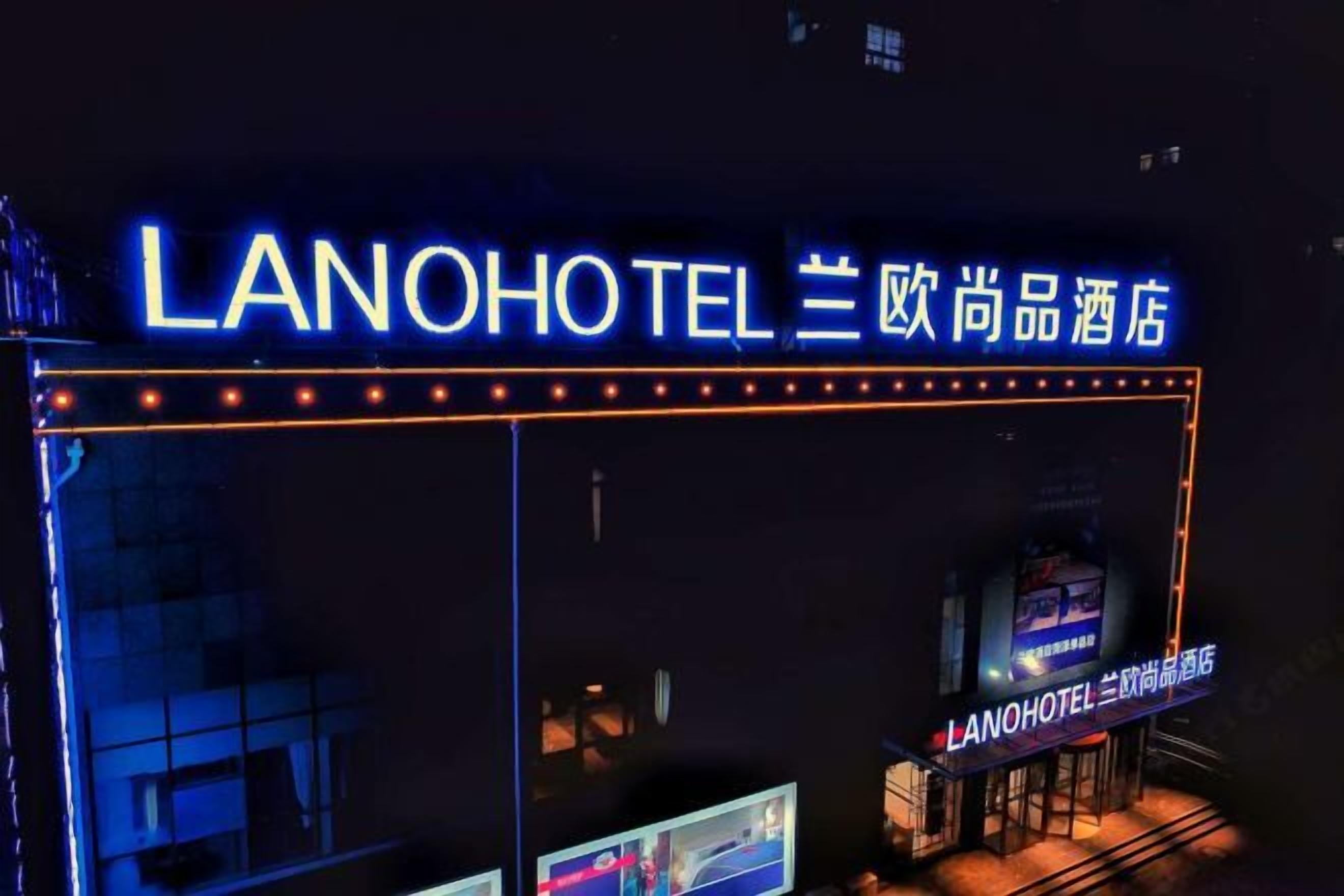 A hotel entrance with illuminated signage in both English and Chinese, indicating the name and brand.