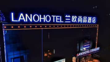 A hotel entrance with illuminated signage in both English and Chinese, indicating the name and brand.