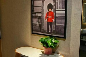 Une photo encadrée d’un gardien en uniforme, un pot de fleurs et une petite table.