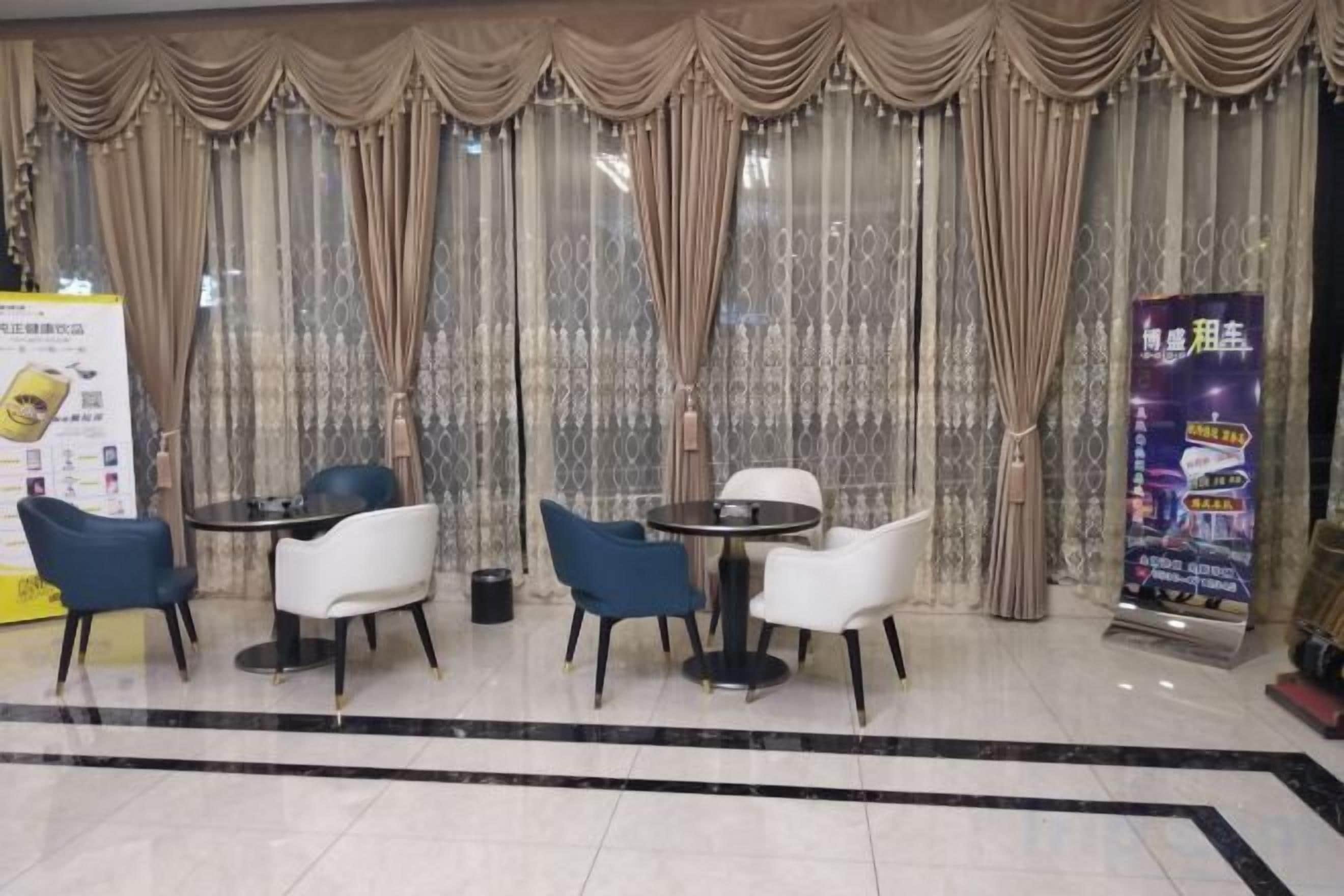 A hotel lobby with a seating area featuring round tables and chairs, a marble floor, and a large window with curtains.