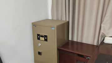 A beige filing cabinet with a lock and a keyhole, positioned next to a wooden desk with a drawer.