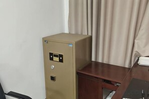 A beige filing cabinet with a lock and a keyhole, positioned next to a wooden desk with a drawer. - LanOuShangPin Hotel (Shan County Central Hospital Yinzuo) (Shan County)