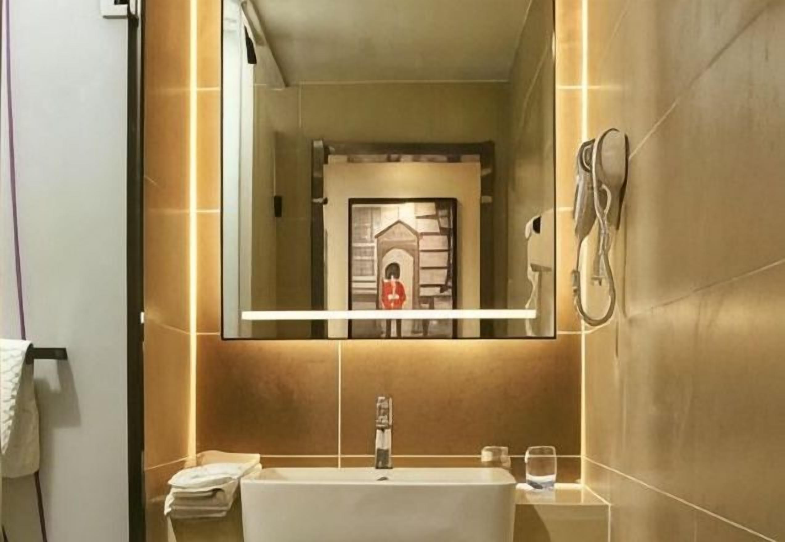 A bathroom with a large mirror, a sink, and a shower.