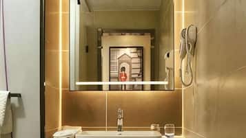 A bathroom with a large mirror, a sink, and a shower.