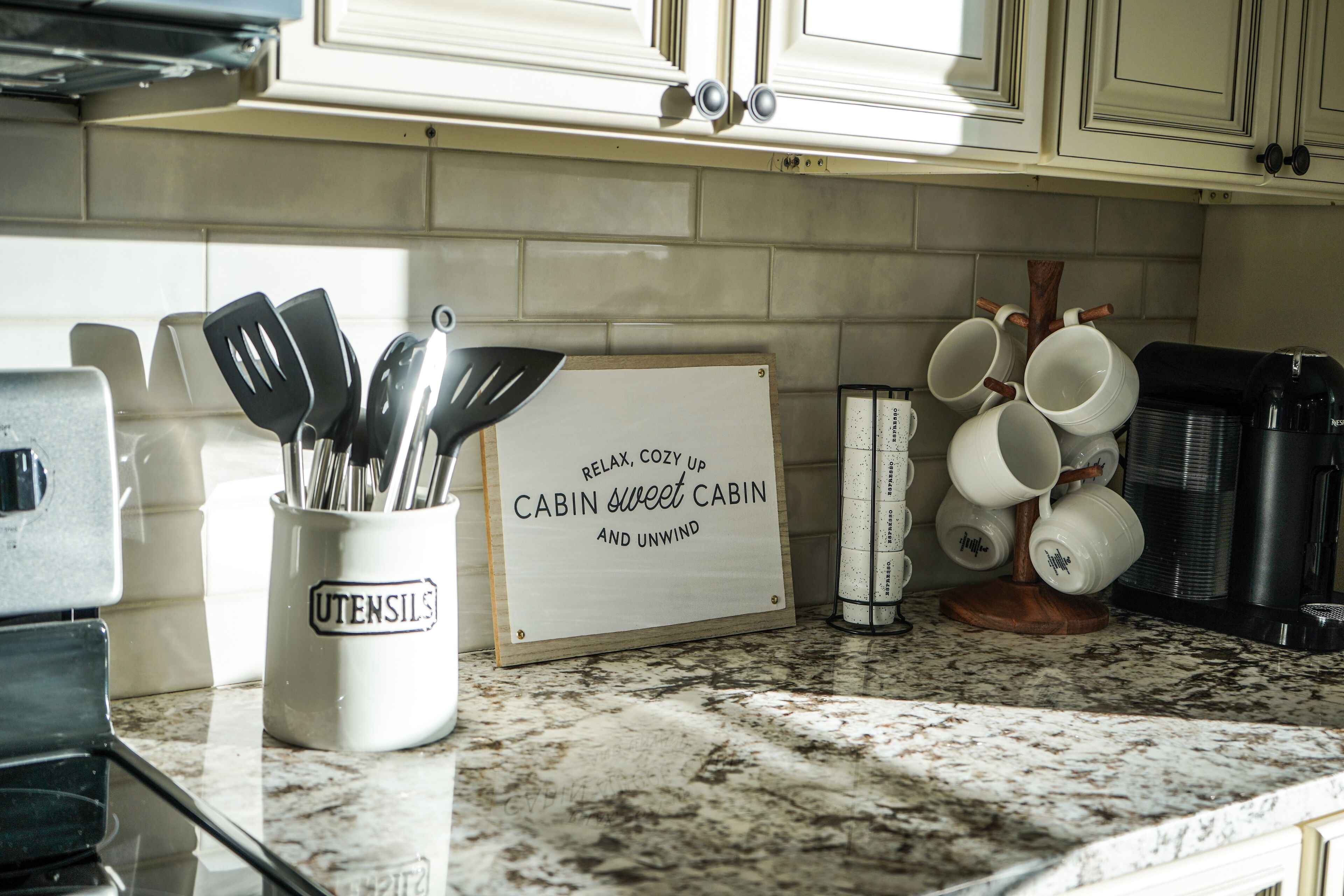 A kitchen counter with a utensil holder, a sign, and a coffee machine.