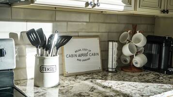 A kitchen counter with a utensil holder, a sign, and a coffee machine.