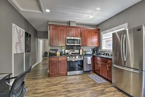 A modern kitchen with wooden cabinets, stainless steel appliances, and a hardwood floor.