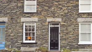 A stone building with a black door, a blue door, and a number 14 on the door.
