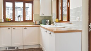 A kitchen with white cabinets, a wooden countertop, a window with a view, and a built-in stove.