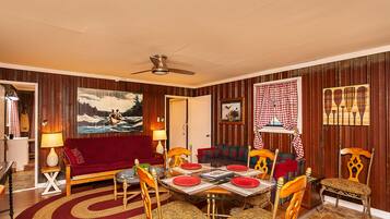 A room with a red sofa, a wooden dining table with red tablecloths, and patterned chairs.