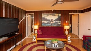 A living room with a television, sofa, coffee table, and a painting on the wall. - Sasquatch Cabin (Benton)