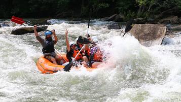 A group of people in an orange raft navigating through a river with rapids.