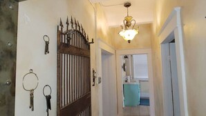A hallway with a decorative metal gate, a light fixture, and a bathroom visible in the background. - 502 W Robertson St. Memphis, TX · Converted Historic Jailhouse (Memphis)