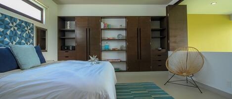 A bedroom with a bed, a bookshelf, a chair, and a geometric wall design.