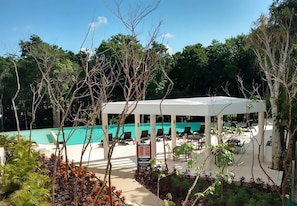 Un espace extérieur abrité comprenant une piscine, des chaises longues et un panneau d’affichage.