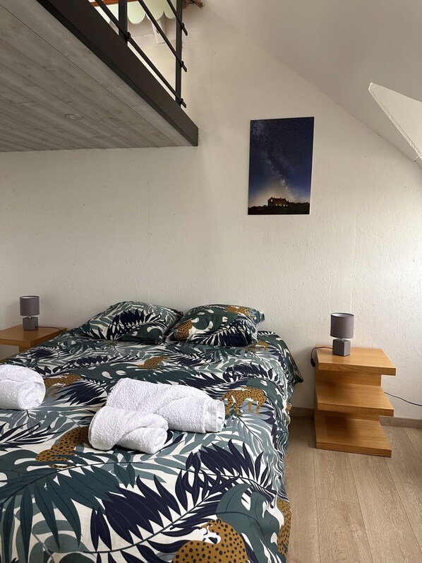 A bedroom with a bed, two bedside tables, a nightstand, a painting, and a staircase. - Cozy, modern house 50 meters from the ocean (Trébeurden)
