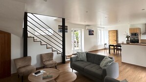 A modern living room with a grey sofa, two round coffee tables, and a staircase leading to another level. - Warm, modern house 50m from the sea (Trébeurden)