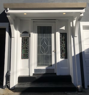 Stylish entrance with a geometric glass panel design, flanked by unique glass panels and a covered porch.