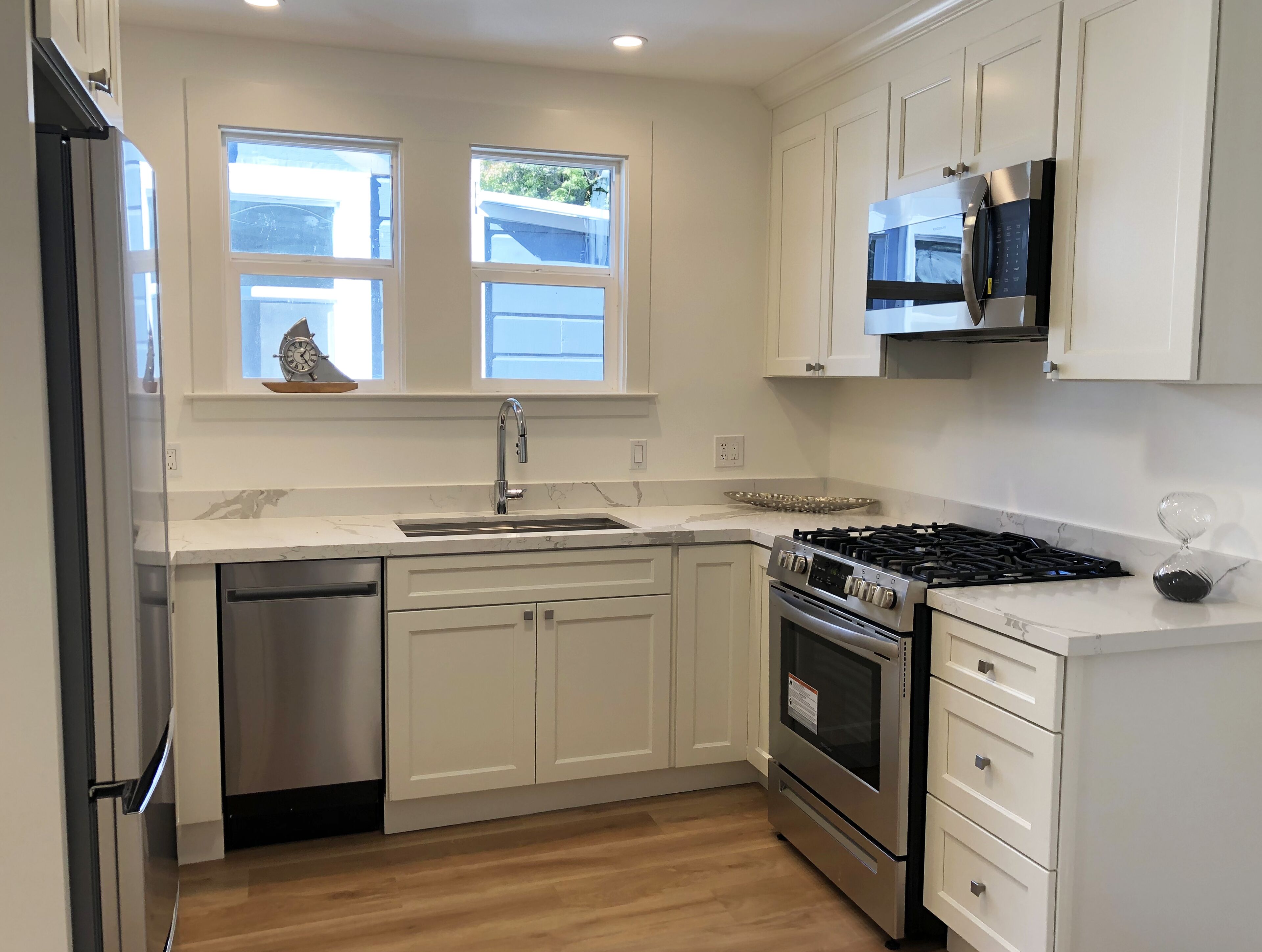 A modern kitchen with white cabinetry, a stainless steel stove, a microwave, and a dishwasher.