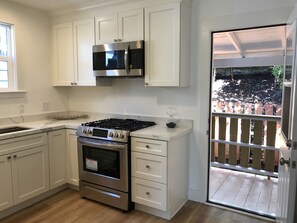 Enjoy cooking in this kitchen with a gas stove, microwave, and oven, and access to a balcony with outdoor views.