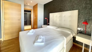 A modern hotel room with a large bed, a wooden wardrobe, and a view of a balcony. - Apartment in front of Fira Gran Via (Hospitalet de Llobregat - Barcelona)