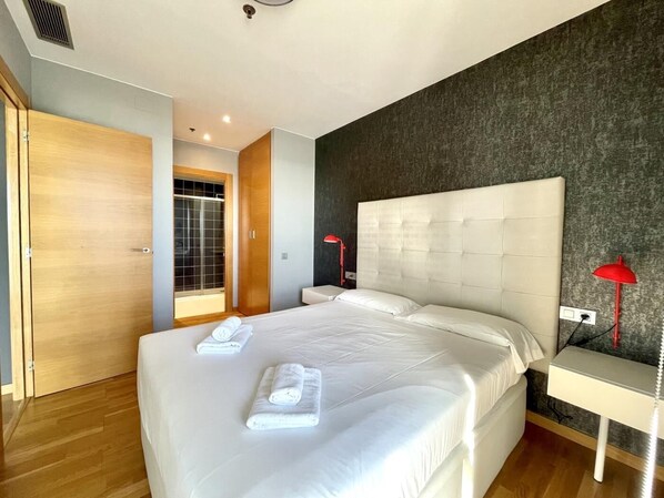 A modern hotel room with a large bed, a wooden wardrobe, and a view of a balcony. - Apartment in front of Fira Gran Via (Hospitalet de Llobregat - Barcelona)