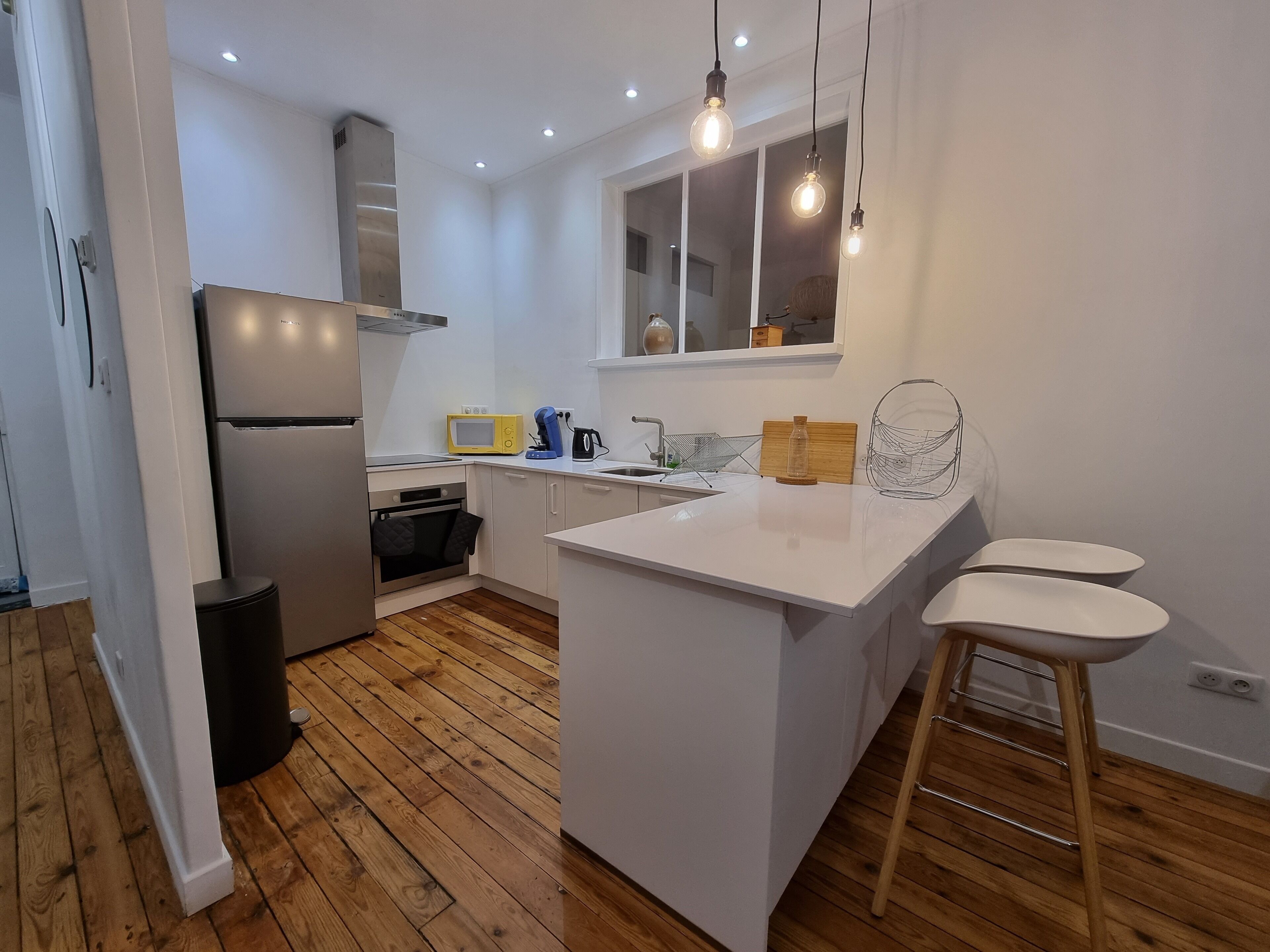 A modern kitchen with white cabinetry, a central island, a built-in oven, and a microwave.
