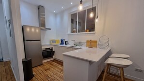 Une cuisine moderne avec des meubles blancs, un îlot central, un four encastré et un four à micro-ondes.