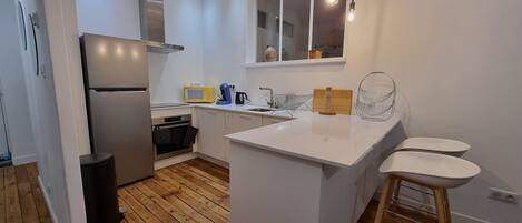 A modern kitchen with white cabinetry, a central island, a built-in oven, and a microwave.