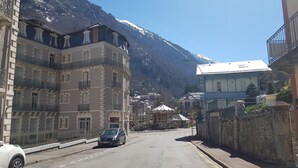 Une rue bordée d’immeubles, une voiture et une montagne en arrière-plan.