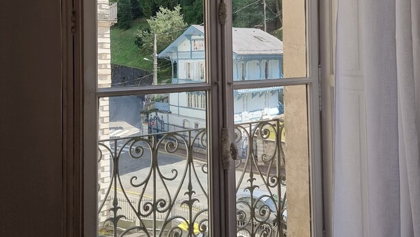 Une fenêtre donnant sur un paysage montagneux et des bâtiments.