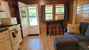 A cozy cabin interior with a kitchenette, a dining area, and a seating area.