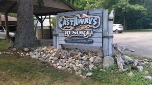A sign for Castaways Resort with a quote, surrounded by rocks and a tree.