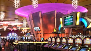 Ein Casino mit mehreren Spielautomaten und einem großen Bildschirm, der Spielergebnisse anzeigt.