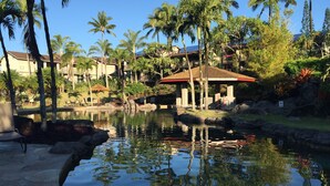 Ein Resort mit Pool, umgeben von Palmen und einem strohgedeckten Gebäude.