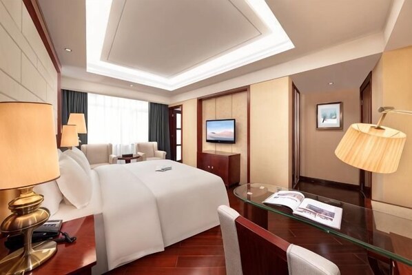 Una habitación de hotel con una cama grande, un escritorio con lámpara, una televisión y una mesa de vidrio.