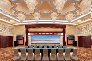 Une salle de conférence dotée d’un grand écran, de rangées de chaises et d’un sol recouvert de moquette.