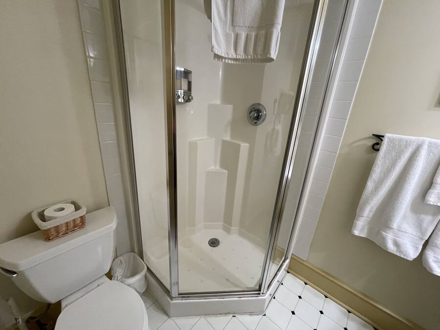 Un baño con ducha de vidrio, inodoro y lavamanos.