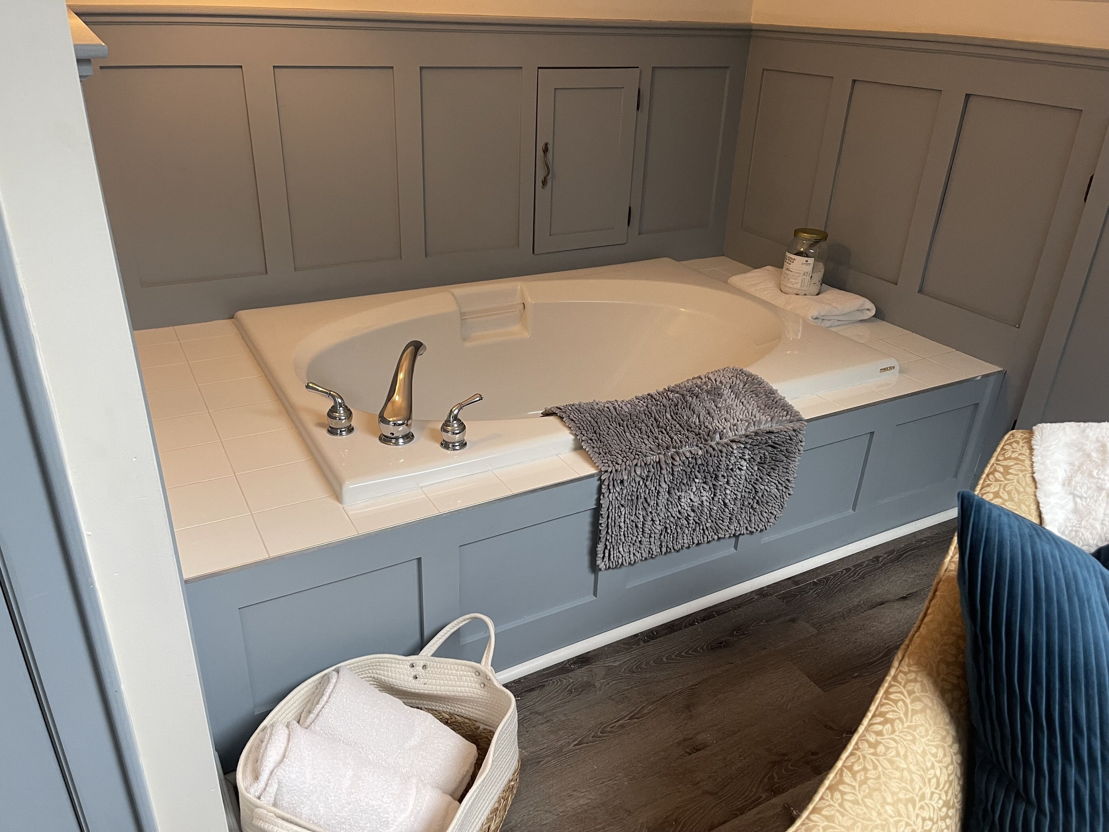 Un baño moderno con una bañera independiente, un perchero y una cesta de mimbre.