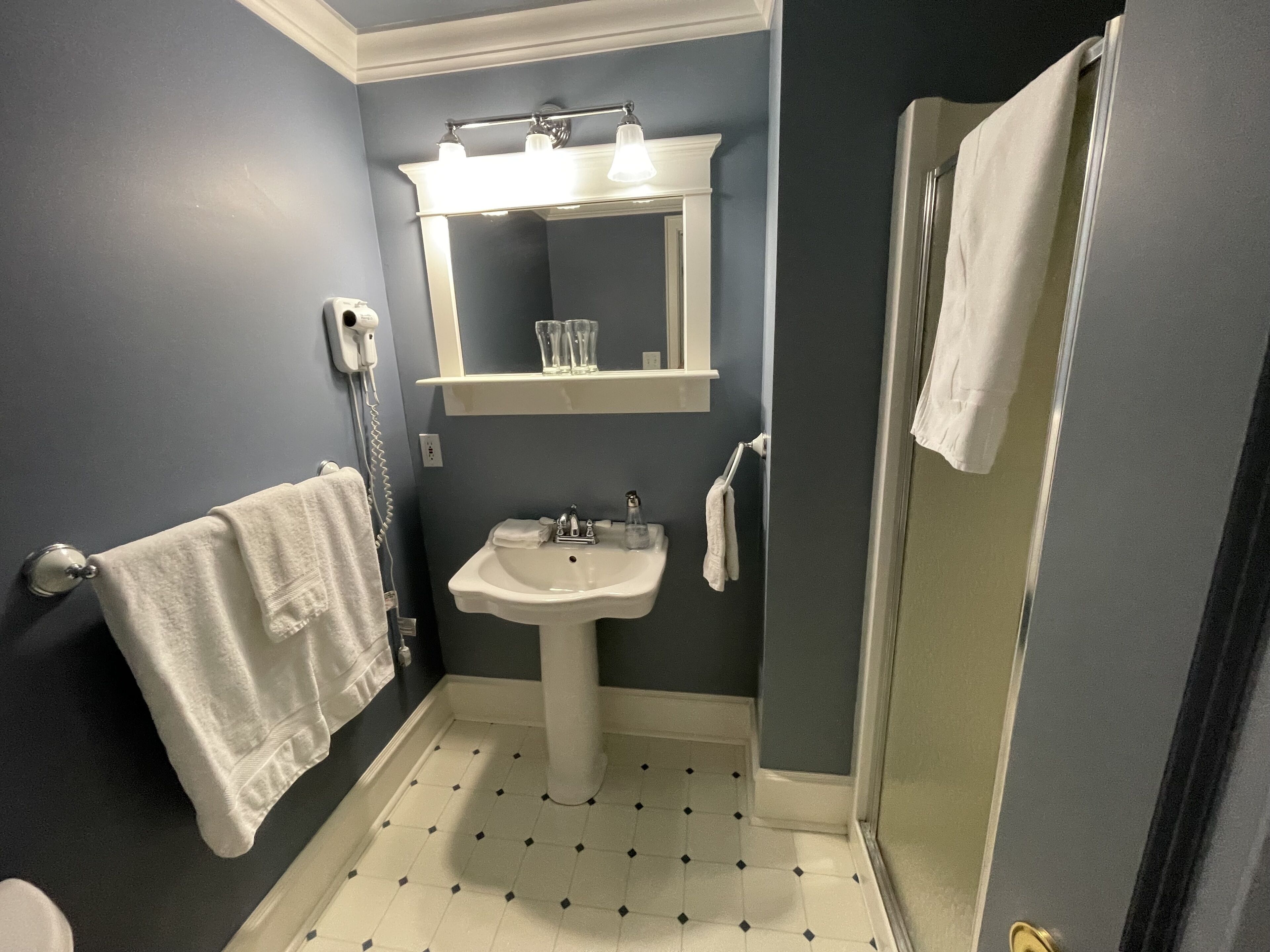 Un bagno con un lavandino bianco, uno specchio e un porta asciugamani.