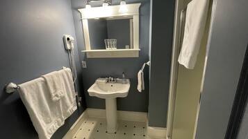 Un bagno con un lavandino bianco, uno specchio e un porta asciugamani.