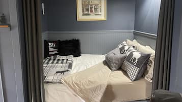 A bedroom with a bed, pillows, a framed picture on the wall, and a window with curtains.
