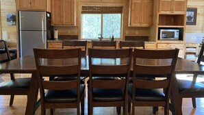 A wooden cabin kitchen with a central island, wooden cabinets, a refrigerator, and a microwave. - Treetop Loft-28 miles to Yellowstone-Owner Operated (Island Park)