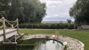 A wooden bridge over a pond, surrounded by a well-maintained lawn and a hedge. - Luxurious country villa nestled in a horse farm on the mountain with great views (Uttenhofen)