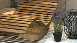 A modern, wooden bench with a slatted design, a black bag, and a potted plant. - Luxurious country villa nestled in a horse farm on the mountain with great views (Uttenhofen)